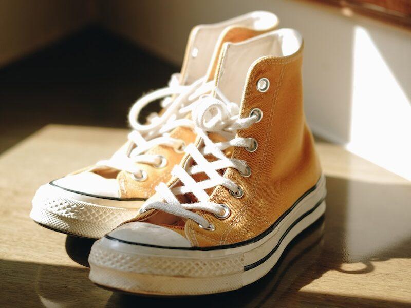 yellow-and-white Converse All-Star high-top sneakers on brown wooden staircase